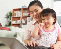 Image of woman holding a child and looking at a computer