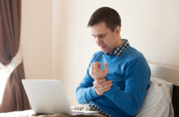 [Image of man holding his wrist and looking at a computer] Click the button below for appointment information and forms.